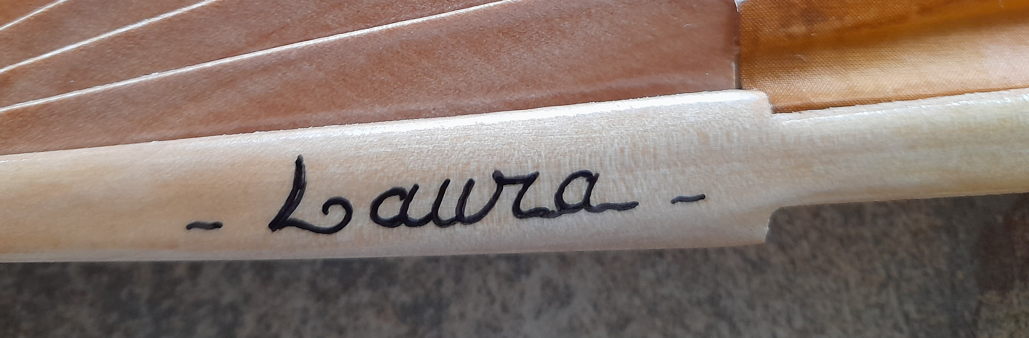 Signature artisanale Nana gravée sur une branche d'éventail en bois.