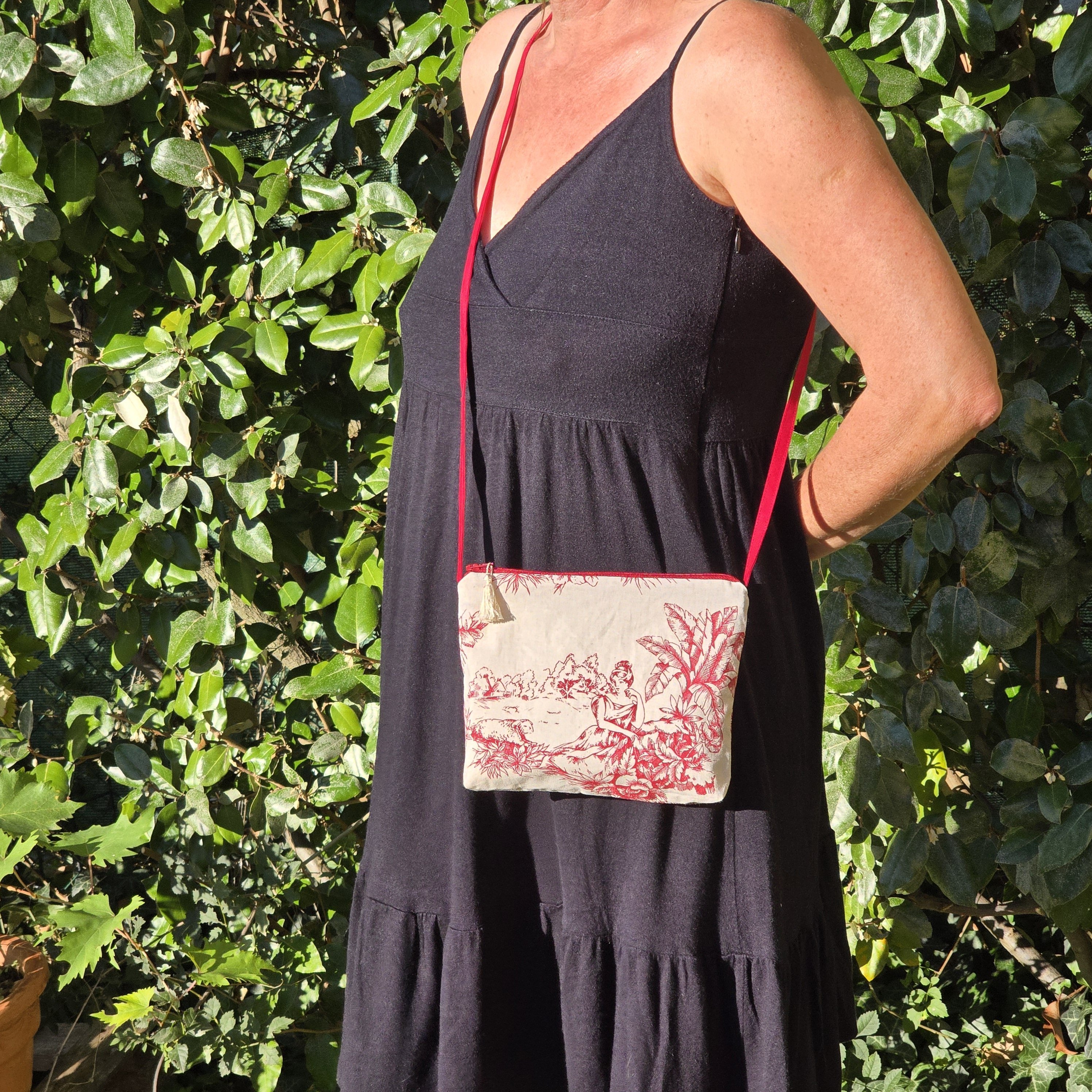 Pochette avec bandouli&egrave;re en tissu toile de Jouy bordeaux et &eacute;cru agr&eacute;ment&eacute;e d'un pompon