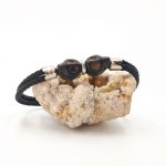 Dubbele schedel en gekruiste botten armband met zwarte stenen op dubbel touw