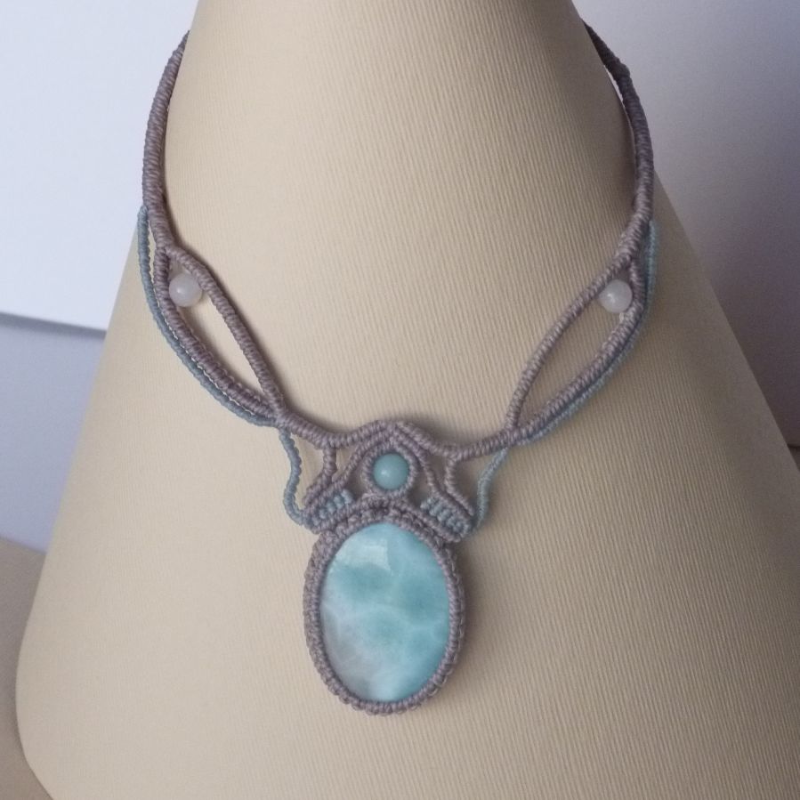 Ketting in taupegrijs/roestblauw micro-macramé met een natuurlijke edelsteen in zachte tinten wit en lichtblauw als middelpunt.