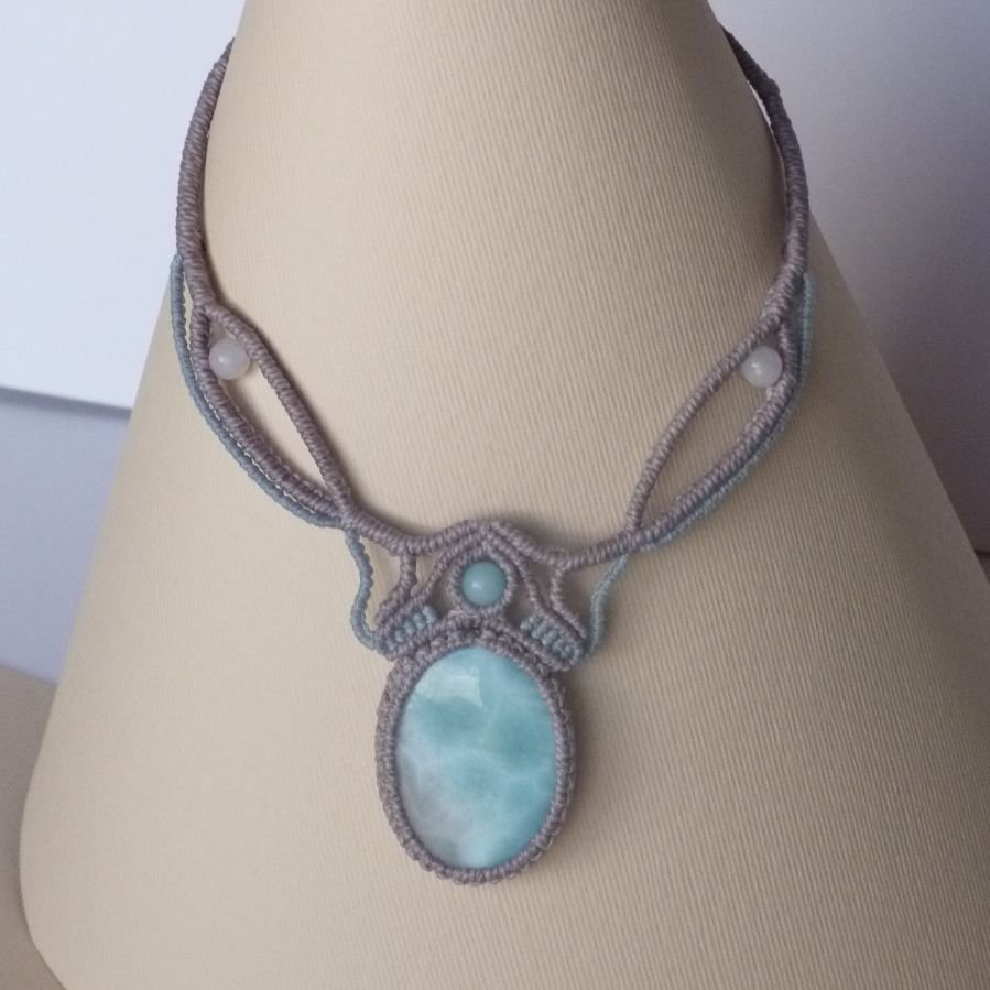 Ketting in taupegrijs/roestblauw micro-macramé met een natuurlijke edelsteen in zachte tinten wit en lichtblauw als middelpunt.