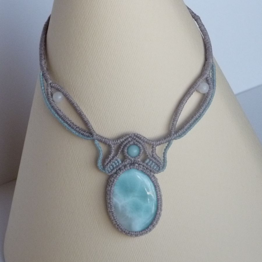 Ketting in taupegrijs/roestblauw micro-macramé met een natuurlijke edelsteen in zachte tinten wit en lichtblauw als middelpunt.