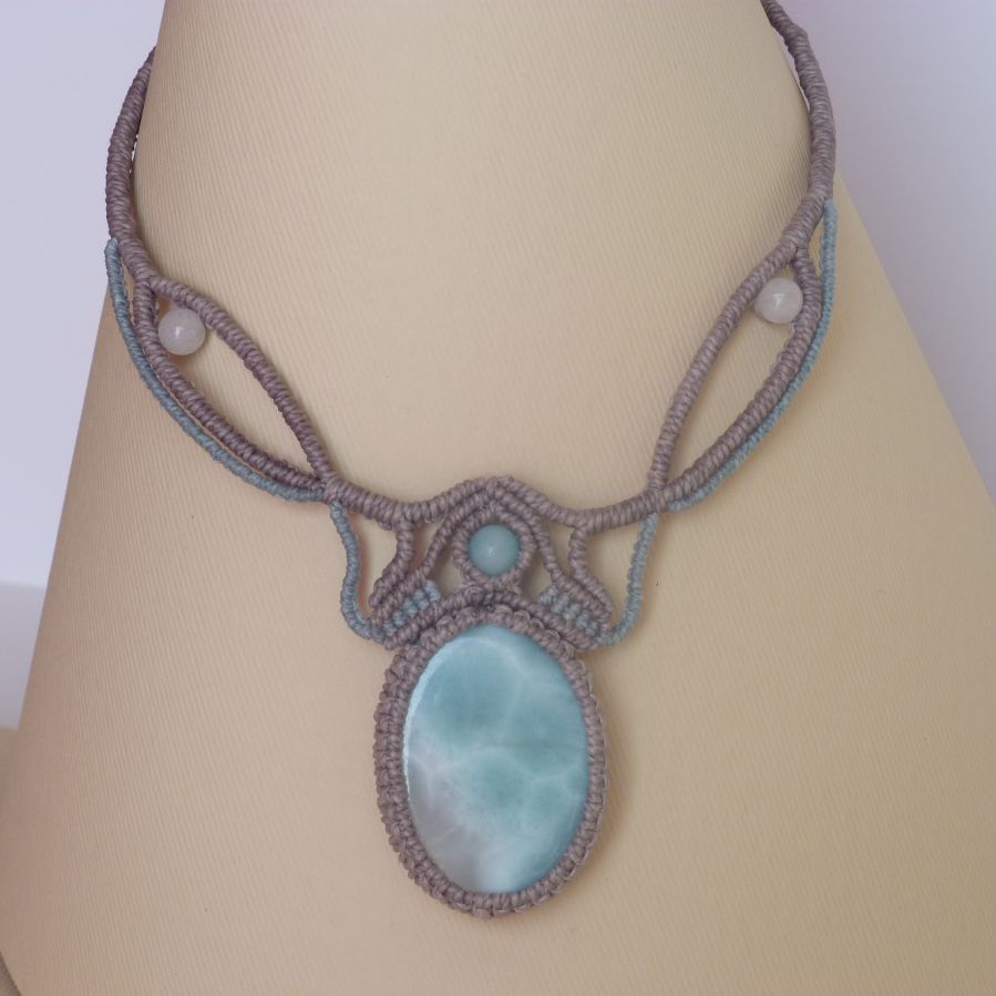 Ketting in taupegrijs/roestblauw micro-macramé met een natuurlijke edelsteen in zachte tinten wit en lichtblauw als middelpunt.