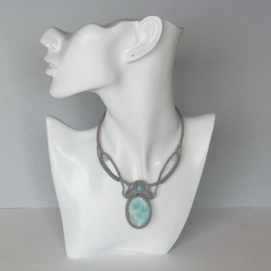 Ketting in taupegrijs/roestblauw micro-macramé met een natuurlijke edelsteen in zachte tinten wit en lichtblauw als middelpunt.