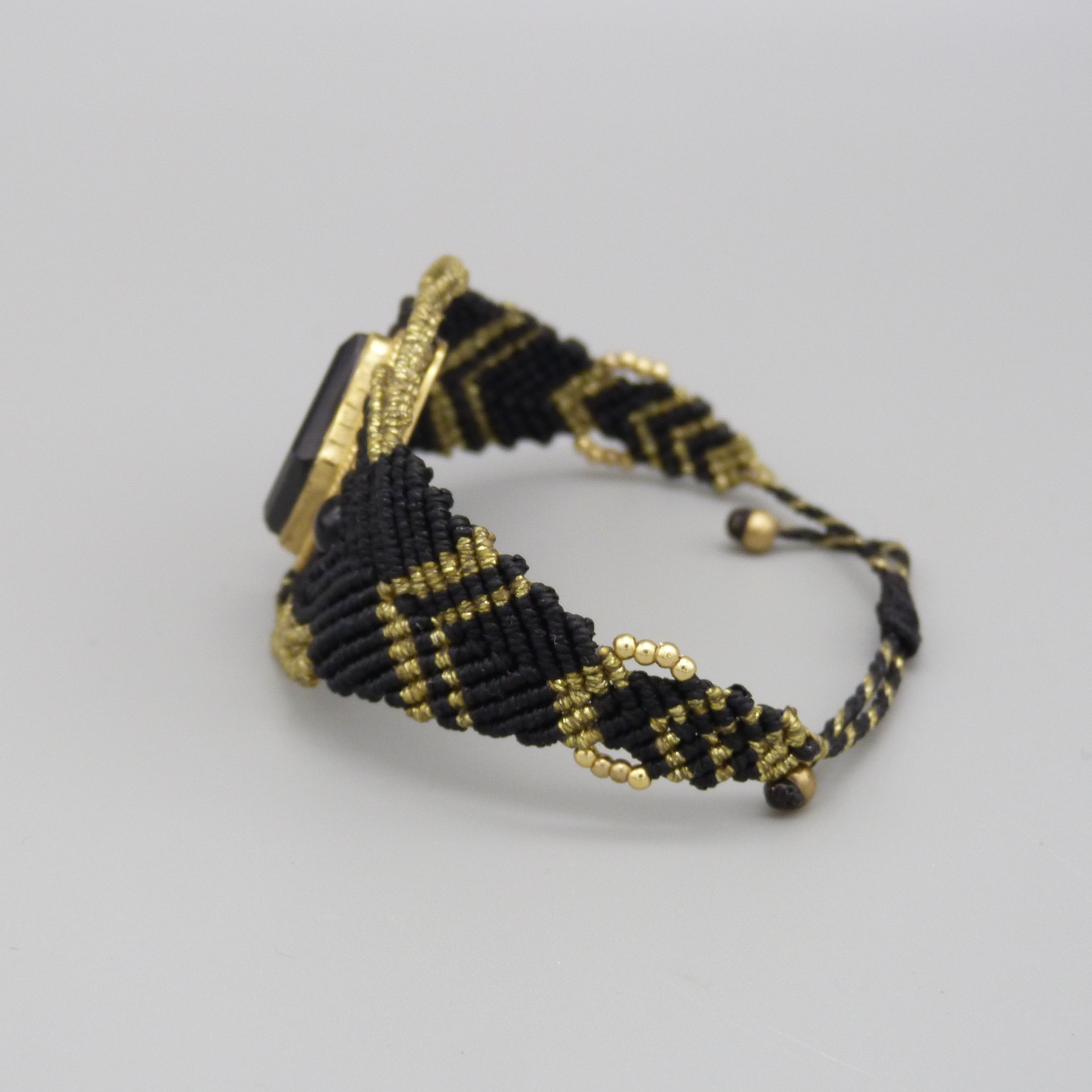 Manchette noire en micro-macram&eacute; avec une pierre onyx noire sertie de laiton