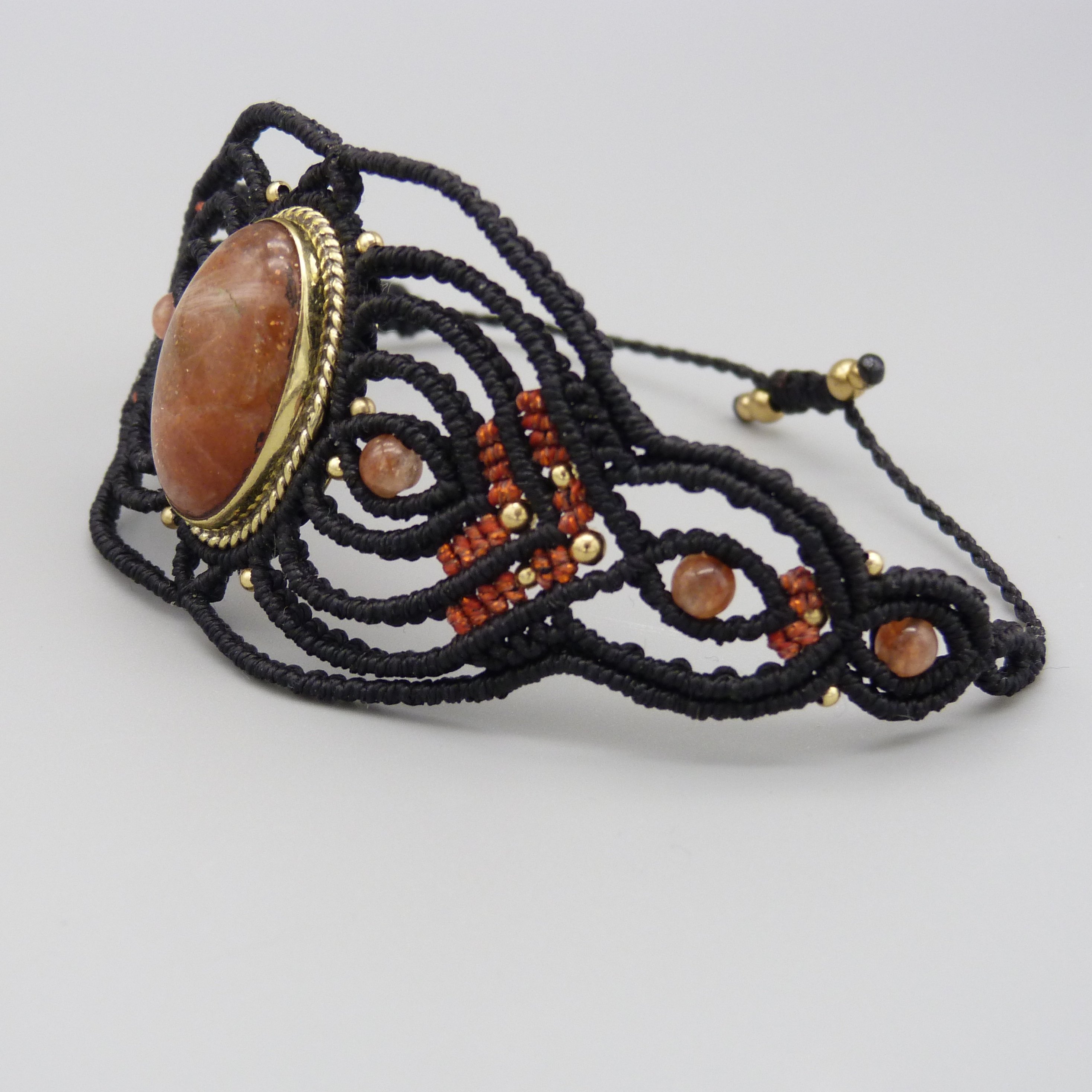 Manchette noire en micro-macramé avec une pierre de soleil