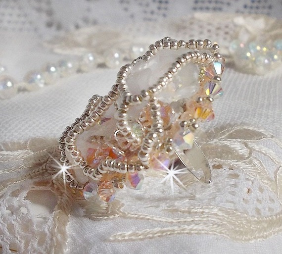 Bouquet d'un Jour ring geborduurd met lucite lelies, Swarovski kristallen tolletjes, een parelmoeren cabochon met zilveren en zalmkleurige rocailles.