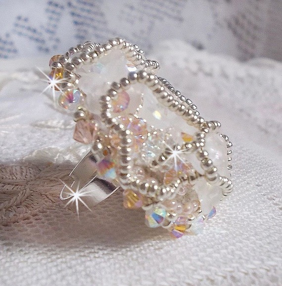 Bouquet d'un Jour ring geborduurd met lucite lelies, Swarovski kristallen tolletjes, een parelmoeren cabochon met zilveren en zalmkleurige rocailles.