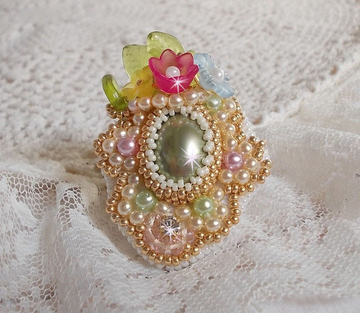 Envolée Fleurie ring geborduurd met een hars cabochon van Lucite bloemen, parels en rocailles.