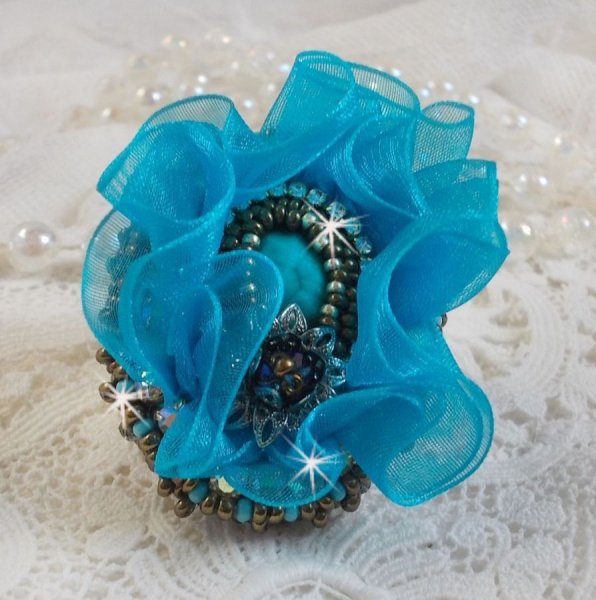 Ilycia Charmante ring geborduurd met een facet geslepen turquoise blauwe hars cabochon en een organza lint