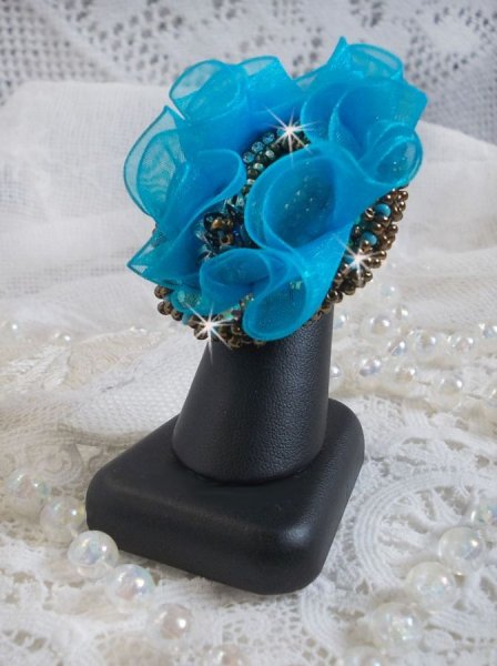 Ilycia Charmante ring geborduurd met een facet geslepen turquoise blauwe hars cabochon en een organza lint
