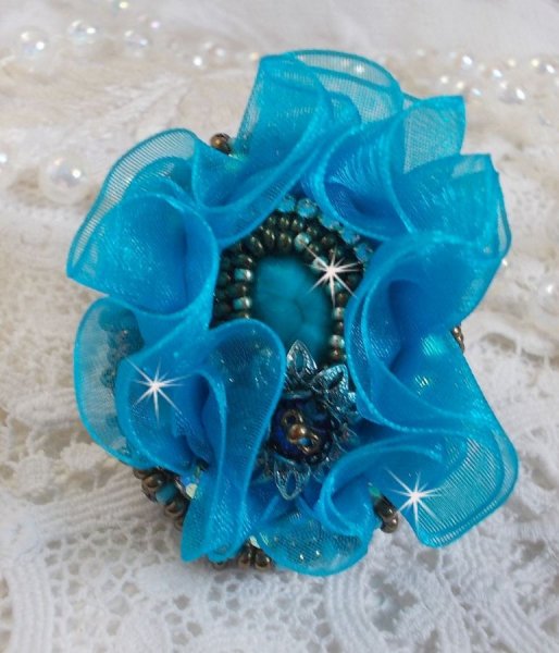 Ilycia Charmante ring geborduurd met een facet geslepen turquoise blauwe hars cabochon en een organza lint