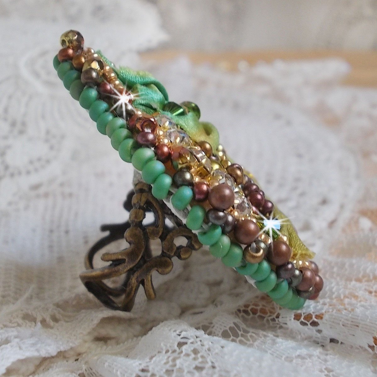 Venetiaanse maanring geborduurd met kameleonkleurig zijden lint, Swarovski kristallen, diverse parels en rocailles.