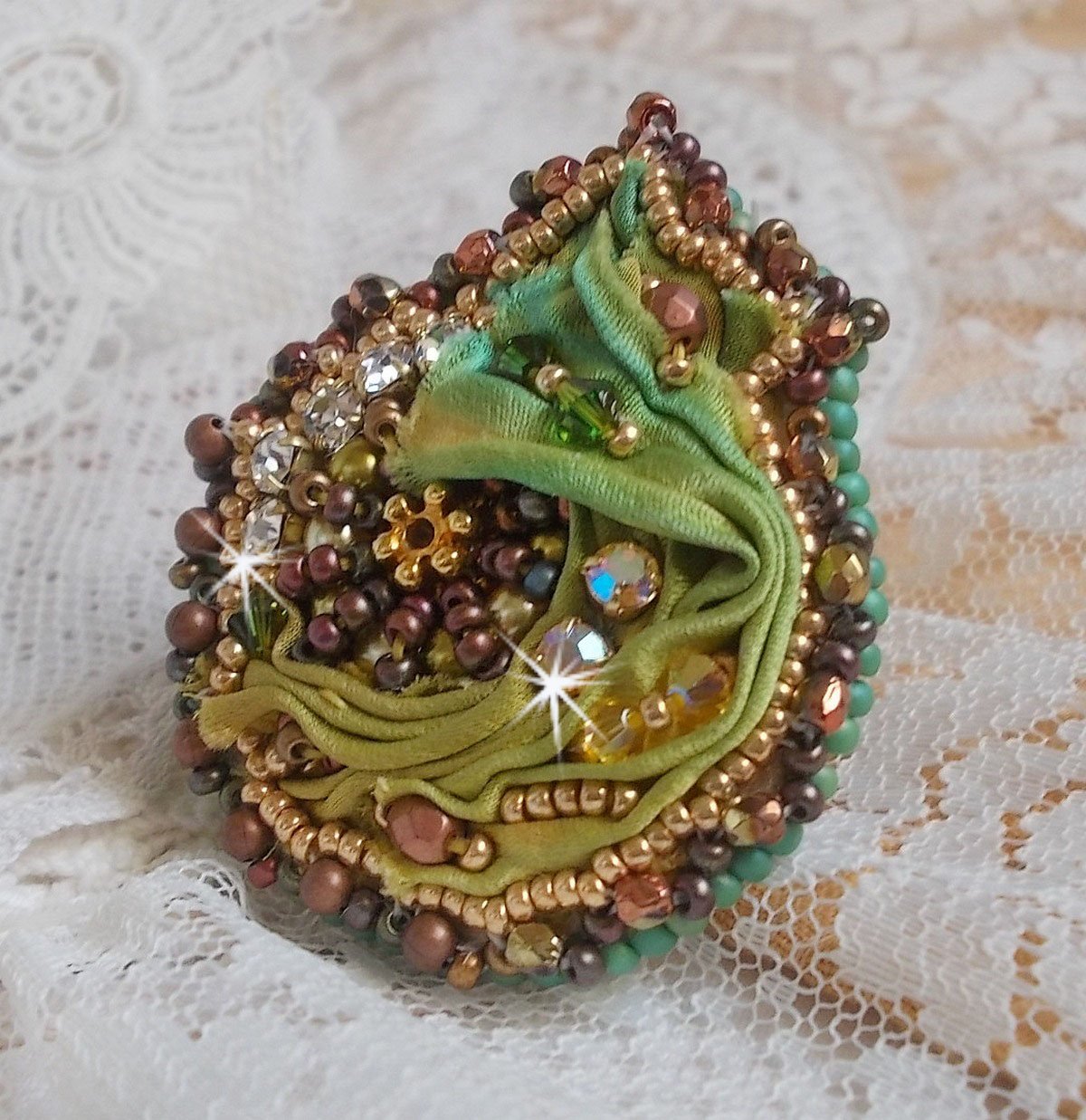Venetiaanse maanring geborduurd met kameleonkleurig zijden lint, Swarovski kristallen, diverse parels en rocailles.
