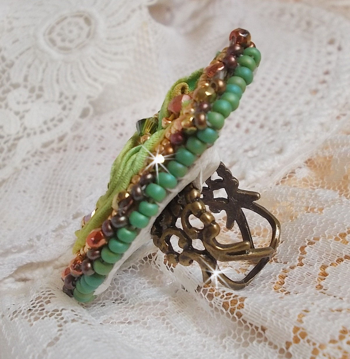 Venetiaanse maanring geborduurd met kameleonkleurig zijden lint, Swarovski kristallen, diverse parels en rocailles.