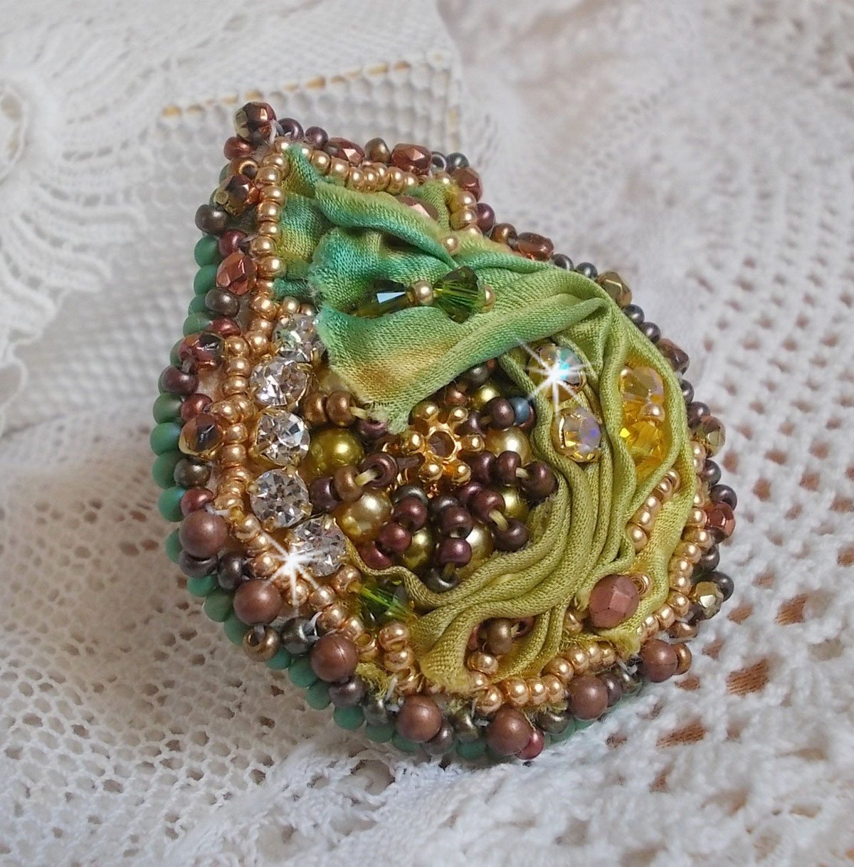Venetiaanse maanring geborduurd met kameleonkleurig zijden lint, Swarovski kristallen, diverse parels en rocailles.