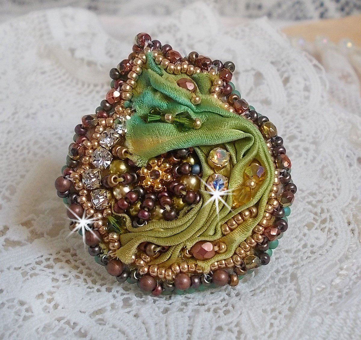 Venetiaanse maanring geborduurd met kameleonkleurig zijden lint, Swarovski kristallen, diverse parels en rocailles.