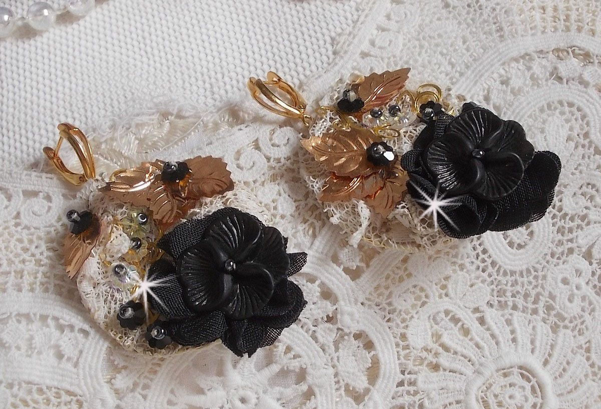 Zwarte en gouden vangers geborduurd met Swarovski-kristallen, stoffen bloemen en rocailles.