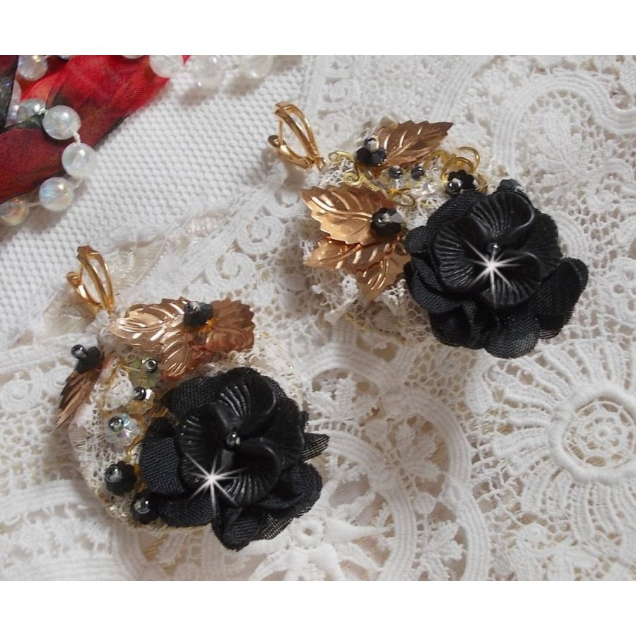 Zwarte en gouden vangers geborduurd met Swarovski-kristallen, stoffen bloemen en rocailles.