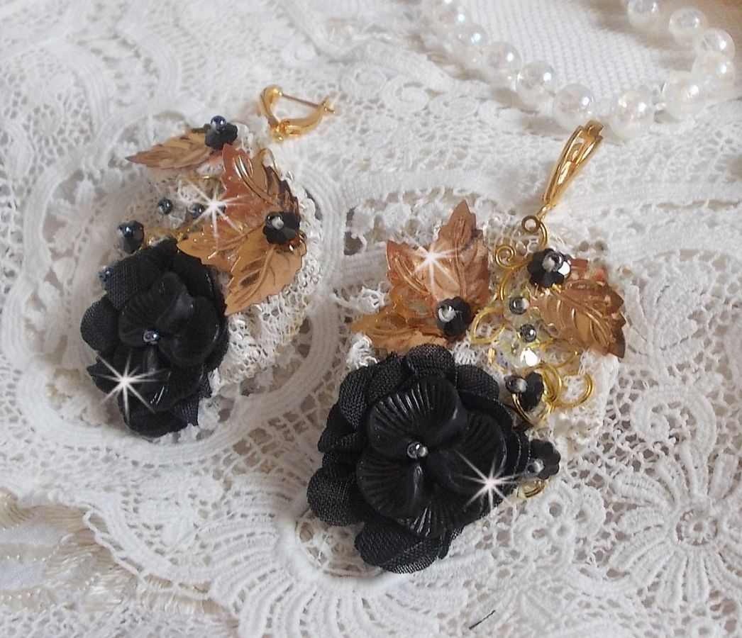 Zwarte en gouden vangers geborduurd met Swarovski-kristallen, stoffen bloemen en rocailles.