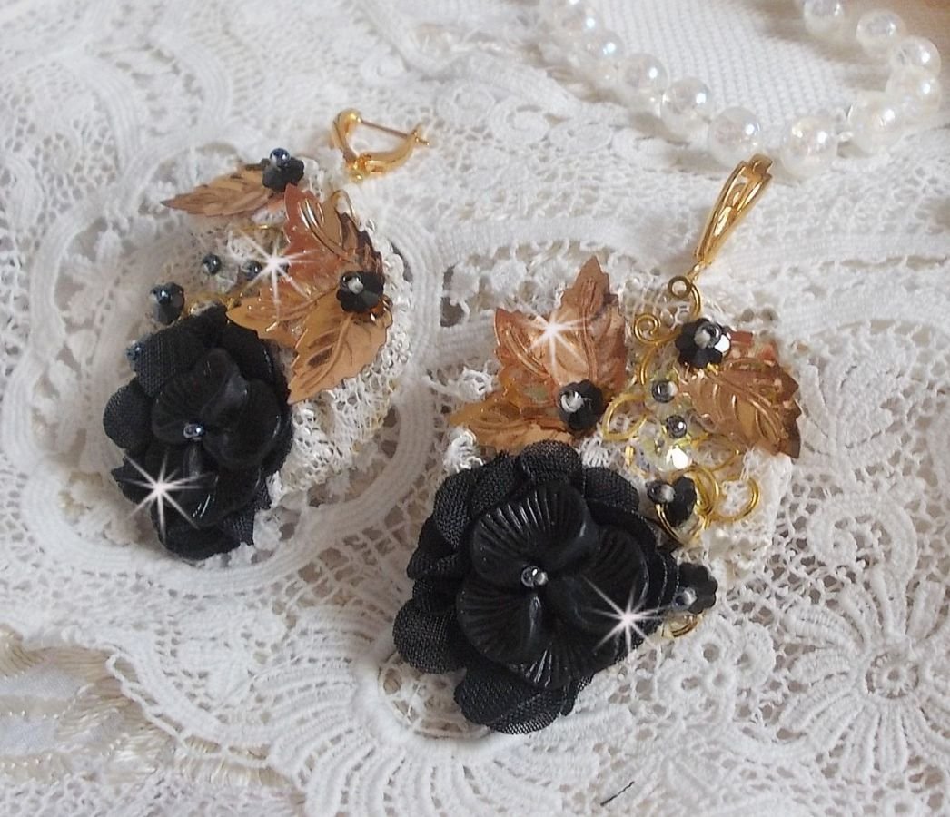 Zwarte en gouden vangers geborduurd met Swarovski-kristallen, stoffen bloemen en rocailles.