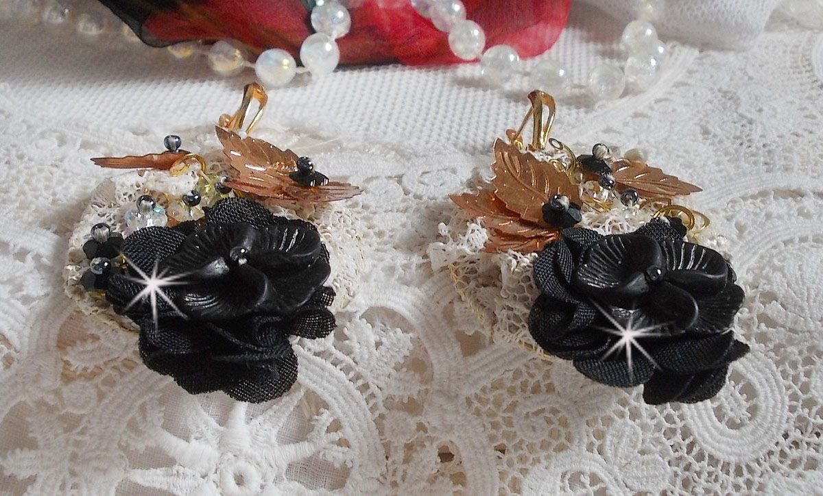 Zwarte en gouden vangers geborduurd met Swarovski-kristallen, stoffen bloemen en rocailles.
