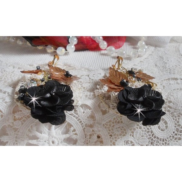 Zwarte en gouden vangers geborduurd met Swarovski-kristallen, stoffen bloemen en rocailles.