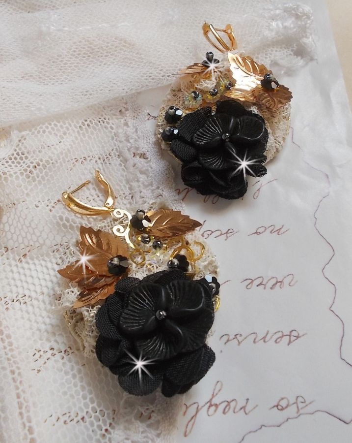 Zwarte en gouden vangers geborduurd met Swarovski-kristallen, stoffen bloemen en rocailles.