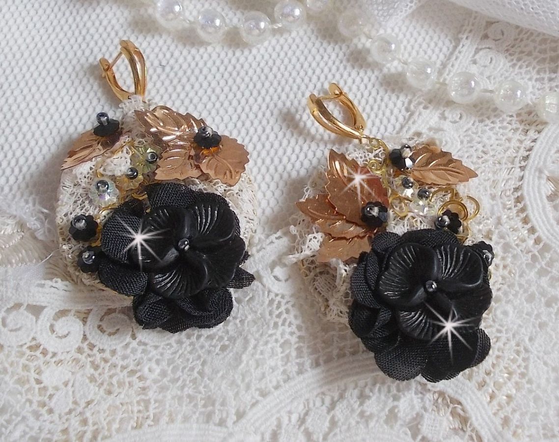 Zwarte en gouden vangers geborduurd met Swarovski-kristallen, stoffen bloemen en rocailles.