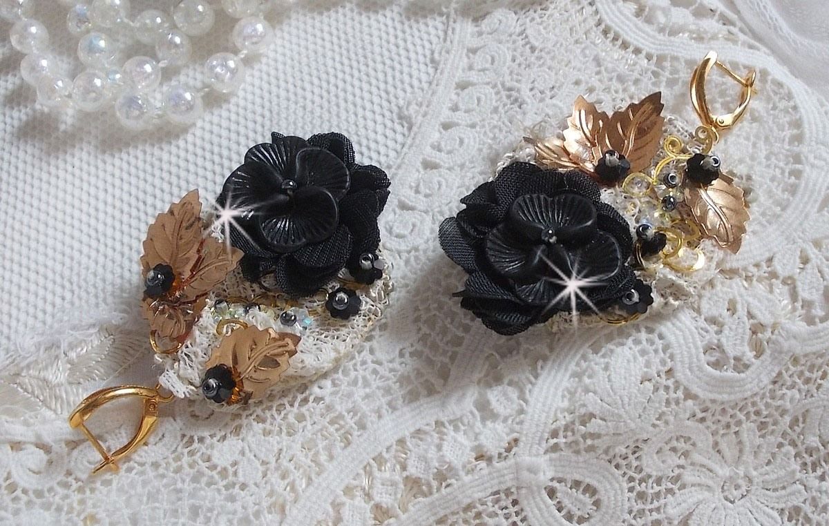 Zwarte en gouden vangers geborduurd met Swarovski-kristallen, stoffen bloemen en rocailles.