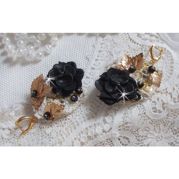Zwarte en gouden vangers geborduurd met Swarovski-kristallen, stoffen bloemen en rocailles.