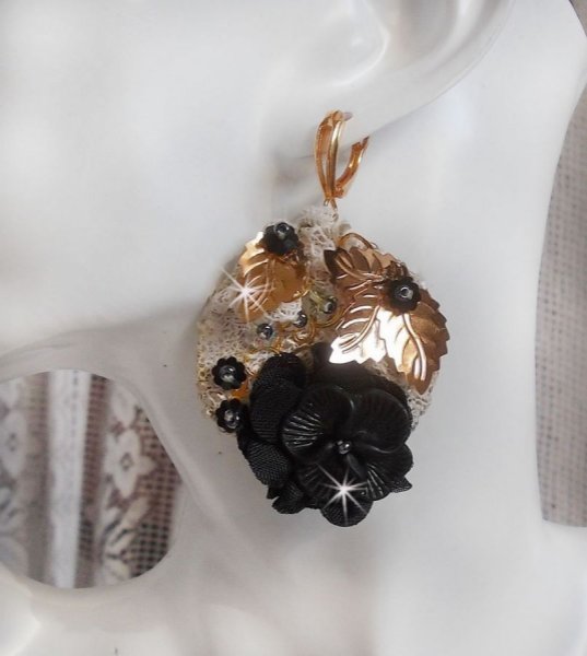 Zwarte en gouden vangers geborduurd met Swarovski-kristallen, stoffen bloemen en rocailles.