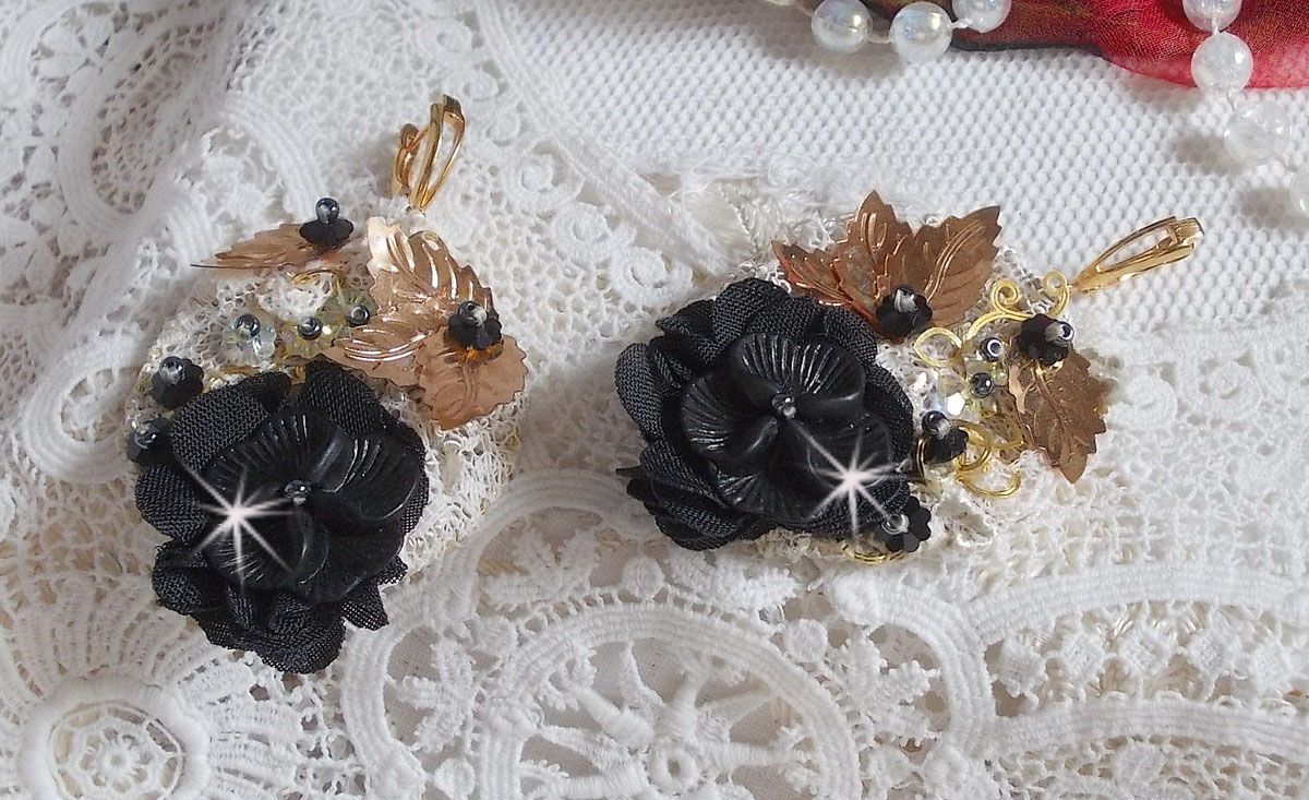 Zwarte en gouden vangers geborduurd met Swarovski-kristallen, stoffen bloemen en rocailles.