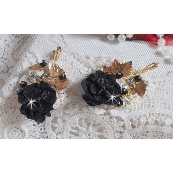 Zwarte en gouden vangers geborduurd met Swarovski-kristallen, stoffen bloemen en rocailles.