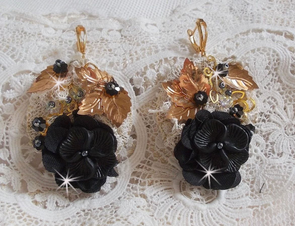 Zwarte en gouden vangers geborduurd met Swarovski-kristallen, stoffen bloemen en rocailles.