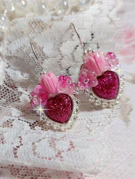 BO C&oelig;ur Ardent mont&eacute;es avec des dormeuses argent&eacute;es &agrave; laquelle s&rsquo;ajoute des c&oelig;urs paillet&eacute;s en r&eacute;sine Fuchsia. Ils sont orn&eacute;s d&rsquo;un bouquet de fleurs en verre &agrave; la couleur Rose pour un style romantique