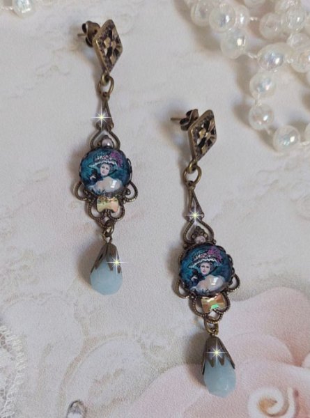 BO Dame au chapeau fleuri repr&eacute;sentant une femme au chapeau entour&eacute; d&rsquo;un ruban noir est mont&eacute; sur des estampes avec des n&oelig;uds en cristal. Une belle &eacute;l&eacute;gance avec ces gouttes en Jade teint&eacute;es de Bleu