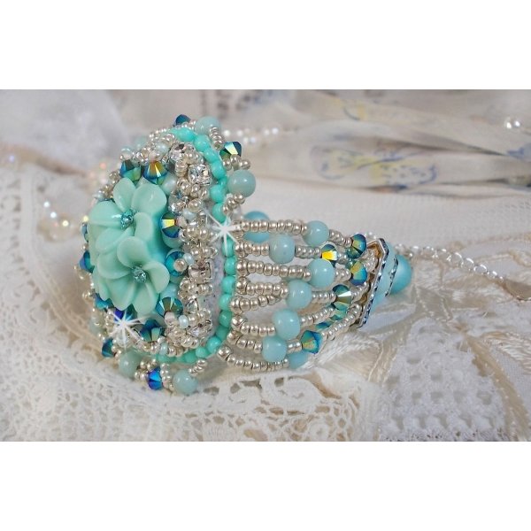 Bracelet Blue Flowers Haute-Couture brodé avec des Cristaux de Swarovski, un cabochon en résine, des perles rondes en satin, des rocailles avec une chaînette et un fermoir en Argent 925/1000