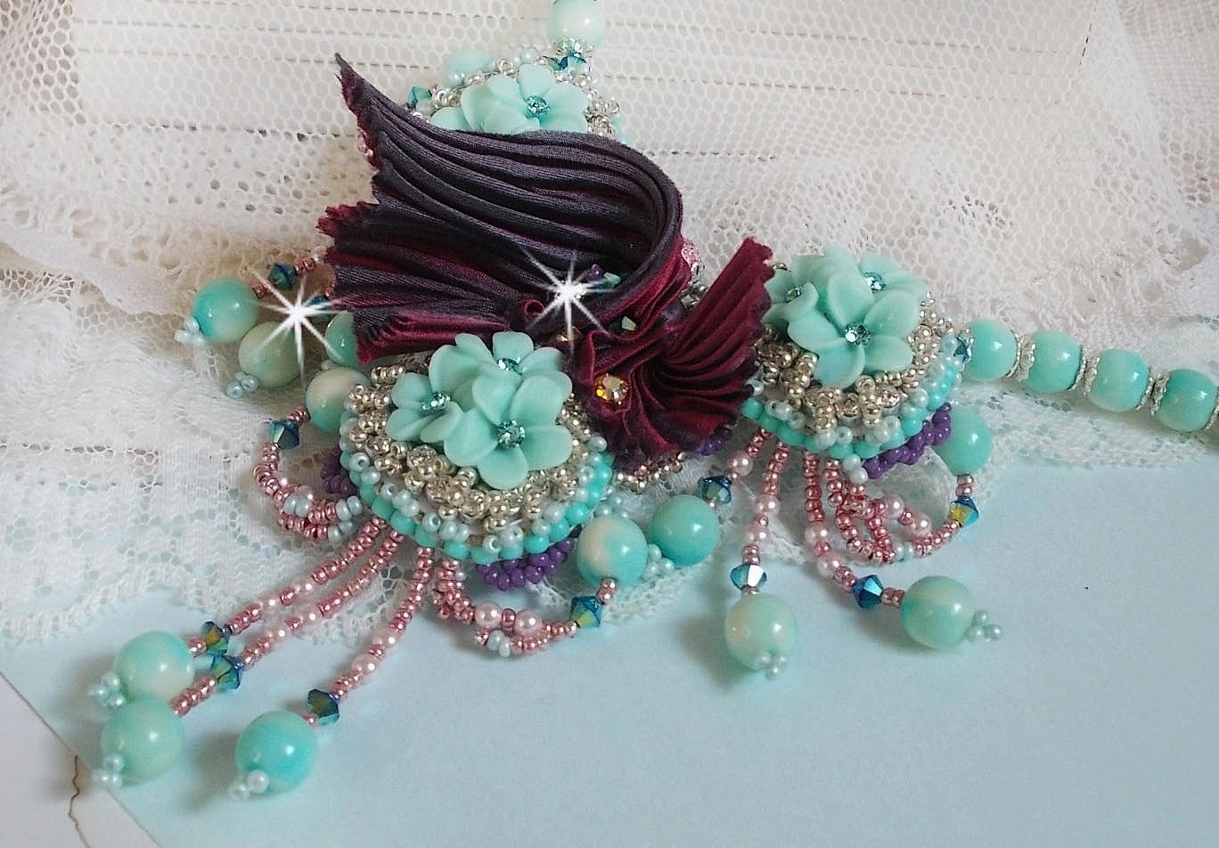 Blue Flowers Haute-Couture ketting geborduurd met Swarovski kristallen, een truffel/framboos zijden lint en rocailles.