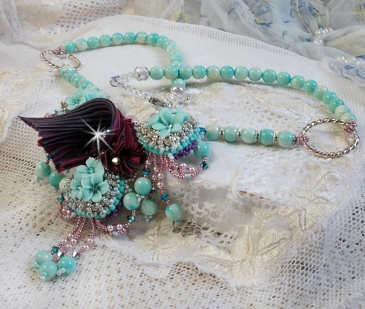 Blue Flowers Haute-Couture ketting geborduurd met Swarovski kristallen, een truffel/framboos zijden lint en rocailles.