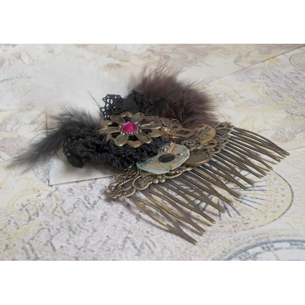 Curiosity Time haarkam gemaakt met zwart kant, diverse accessoires, gouden, zilveren en bronzen bedels met zwarte, bruine en witte veren.