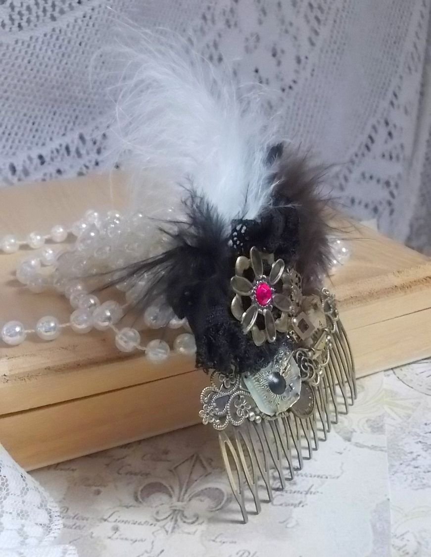 Curiosity Time haarkam gemaakt met zwart kant, diverse accessoires, gouden, zilveren en bronzen bedels met zwarte, bruine en witte veren.