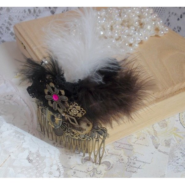 Curiosity Time haarkam gemaakt met zwart kant, diverse accessoires, gouden, zilveren en bronzen bedels met zwarte, bruine en witte veren.