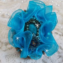 Ilycia Charmante ring geborduurd met een facet geslepen turquoise blauwe hars cabochon en een organza lint